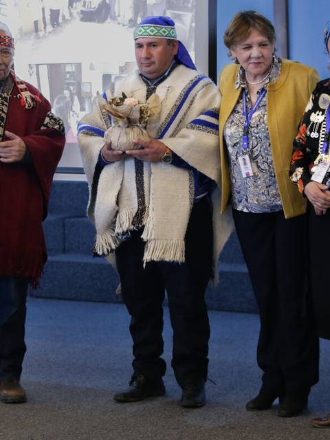 Un grupo de personas con vestimenta tradicional posan sonrientes en un evento.