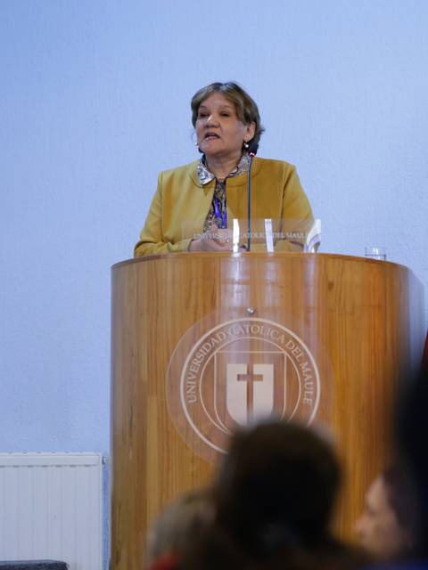 Una mujer habla desde un podio en un evento académico.