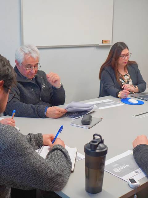 Un grupo de personas discutiendo en una reunión alrededor de una mesa.