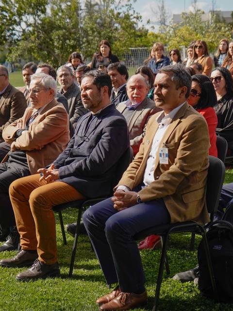 Una multitud de personas sentadas en un evento al aire libre en un jardín.