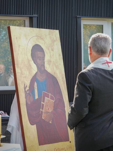 Un sacerdote bendice una imagen sagrada en un evento al aire libre.