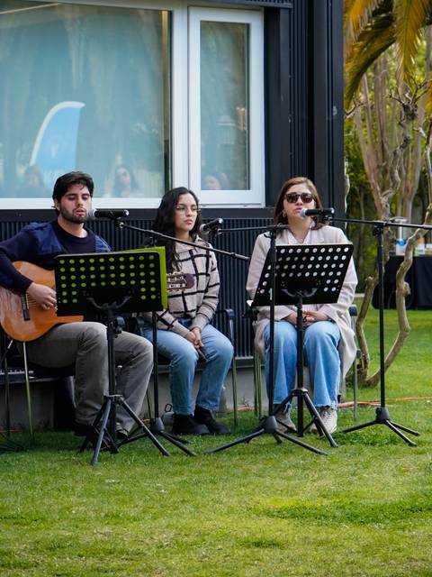 Una ceremonia al aire libre con músicos y una imagen en un caballete.