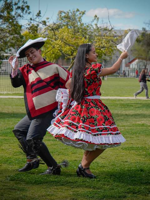 Dos personas bailando en un parque con trajes tradicionales mexicanos.