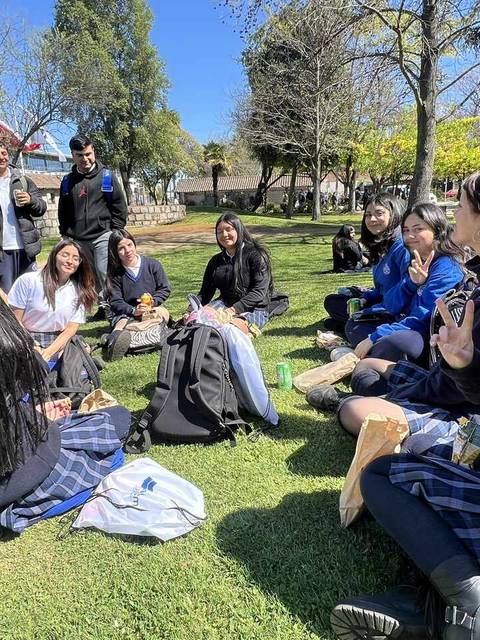 Un grupo de estudiantes se reúne al aire libre en un día soleado para compartir y socializar.