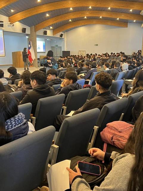 Un auditorio lleno de estudiantes sentados en filas durante una presentación.