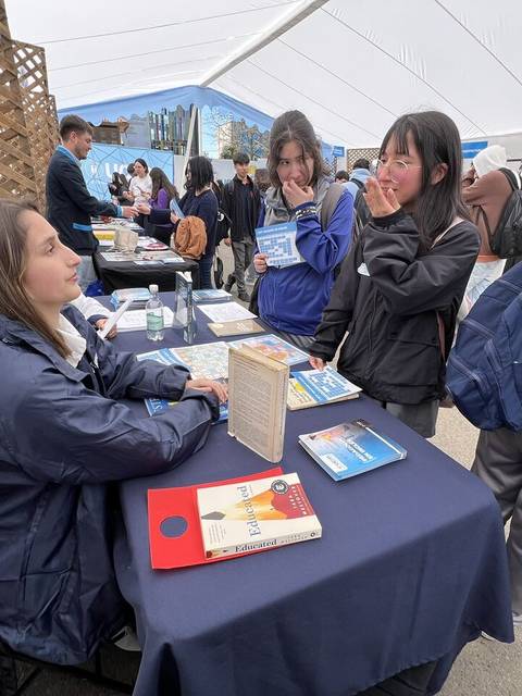 Un grupo de personas interactuando en un evento o feria, con mesas y material informativo en un entorno cubierto.