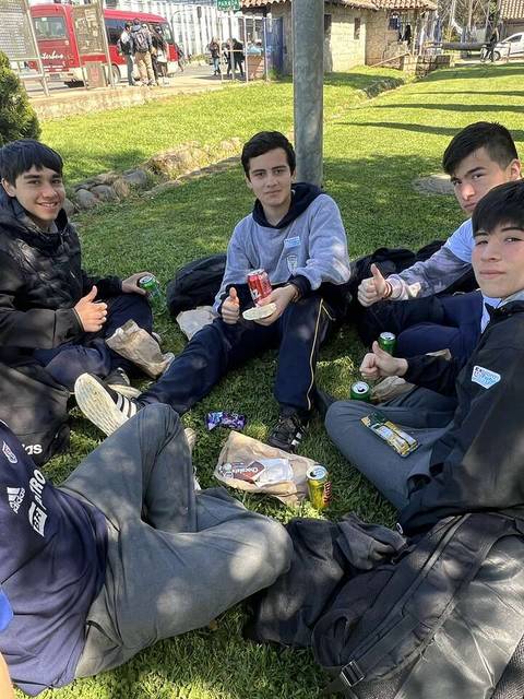 Un grupo de cinco jóvenes sentados en el césped disfrutando de un momento de convivencia.
