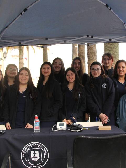 Un grupo de personas sonrientes se reúne bajo una carpa, formando parte de un evento comunitario.