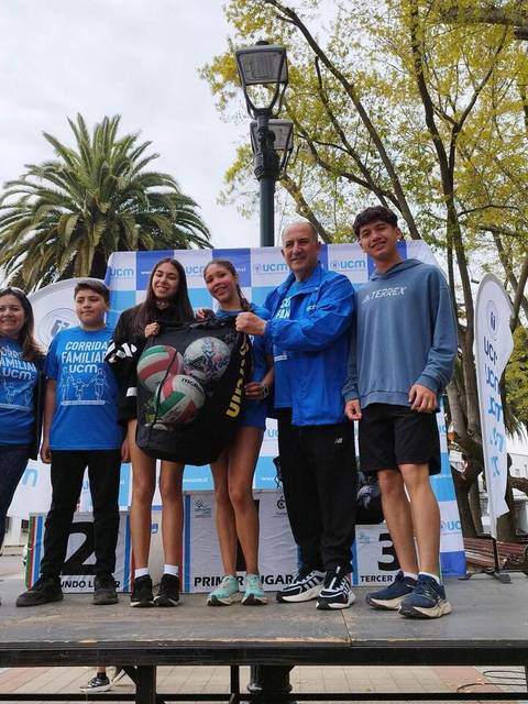 Un grupo de personas pose para una foto en un escenario al aire libre durante un evento comunitario.