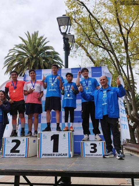 Un grupo de jóvenes atletas celebra en el podio tras una competencia deportiva donde se premian a los ganadores.