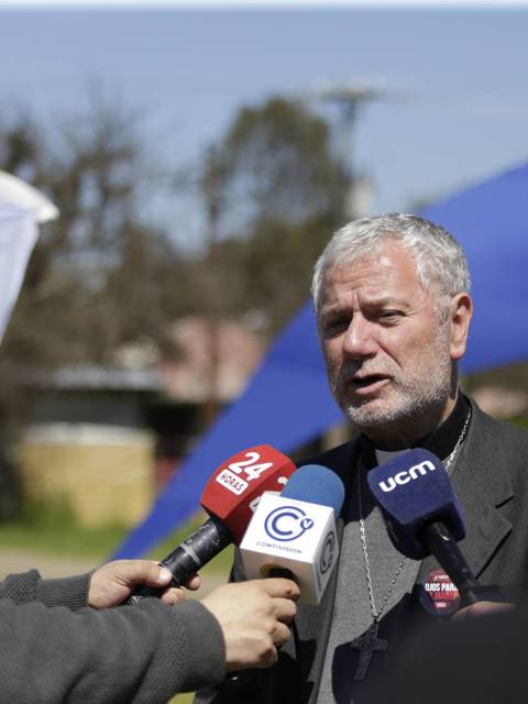 Un hombre habla frente a varios micrófonos durante un evento al aire libre.
