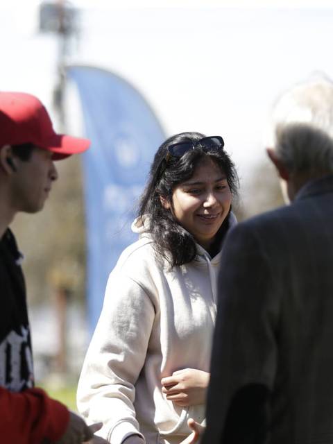 Un grupo de jóvenes y adultos conversan animadamente al aire libre.