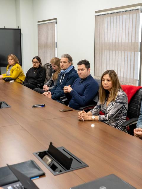 Reunión de un grupo de personas sentadas alrededor de una mesa en una sala de conferencias.