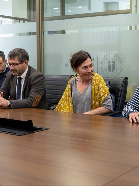 Un grupo de personas sentadas alrededor de una mesa en una sala de reuniones.
