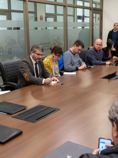 Una reunión de un grupo de personas sentadas alrededor de una mesa en una sala de conferencias.
