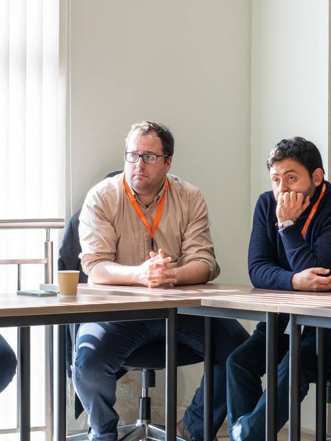 Un grupo de personas sentadas en una sala de reuniones prestando atención.