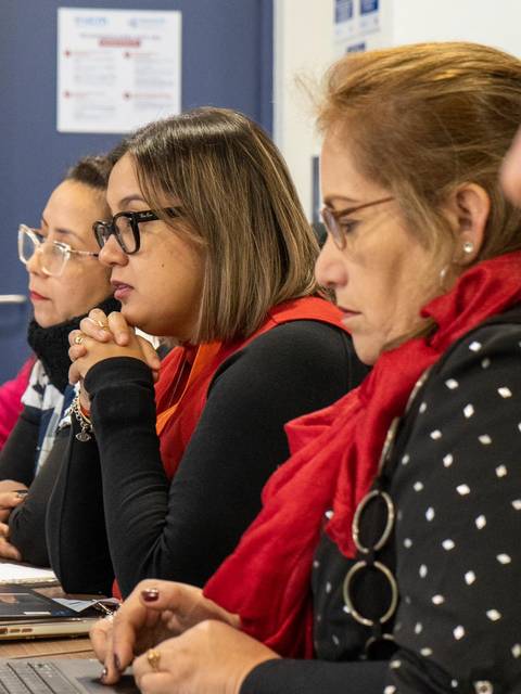 Un grupo de personas concentradas trabajando en laptops durante una reunión.