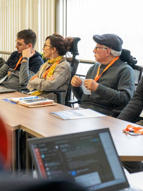 Un grupo de personas sentadas en una sala de reuniones prestando atención durante una presentación.