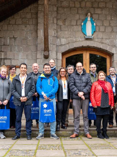 Grupo de personas posando frente a un edificio de piedra.