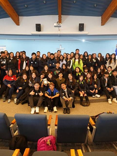 Un grupo numeroso de personas posando juntas en un auditorio.
