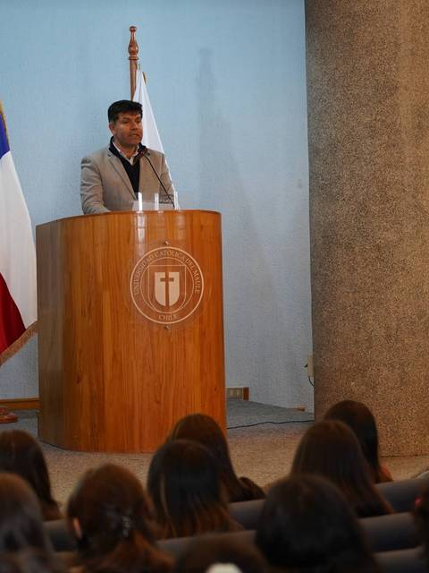 Un orador se presenta frente a una audiencia en un evento formal en Chile.