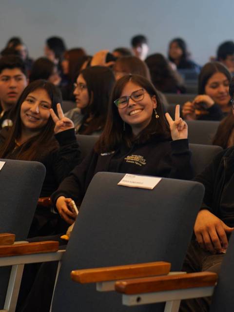 Un grupo de estudiantes sonrientes posan en un auditorio.