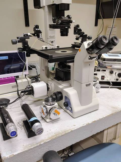 Un microscopio en un laboratorio con varios instrumentos y un monitor.