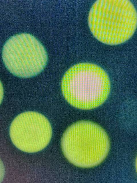 La imagen muestra una serie de círculos difuminados en tonos de verde y rosa sobre un fondo oscuro.