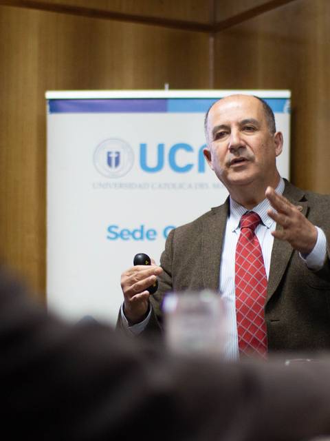 Un orador presenta un tema en un evento mientras escucha a la audiencia.