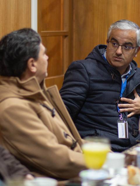 Un grupo de personas está conversando en una reunión mientras disfrutan de un desayuno.