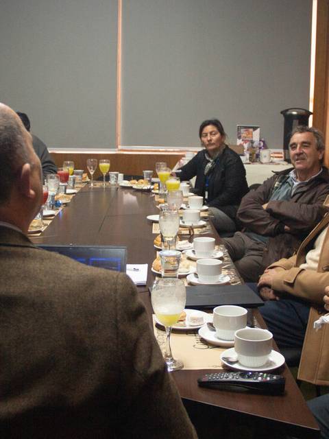 Un grupo de personas reunidas en una sala de conferencia con mesas dispuestas para un desayuno de trabajo.