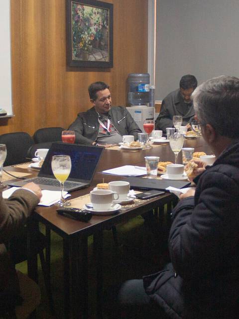 Reunión de trabajo en una sala con varios participantes alrededor de una mesa.