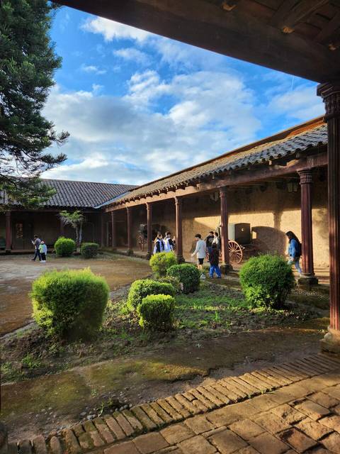Una vista de un patio con personas y vegetación en un entorno arquitectónico tradicional.