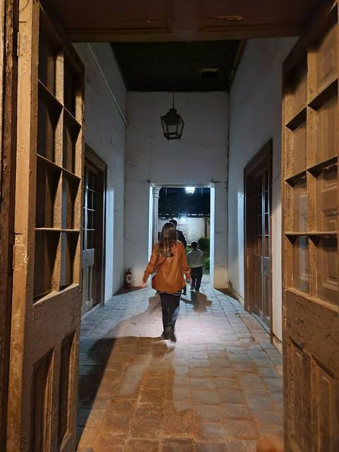 Una persona camina por un pasillo iluminado mientras dos niños la siguen.