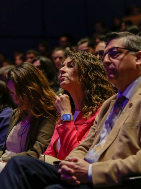 Un grupo de personas sentadas en un auditorio, prestando atención a un evento.