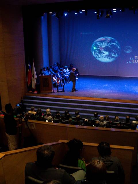 Una conferencia sobre la Tierra y la Luna en un auditorio.