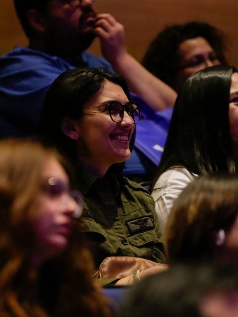 Un grupo de personas sonríe y observa atentamente durante un evento en un auditorio.