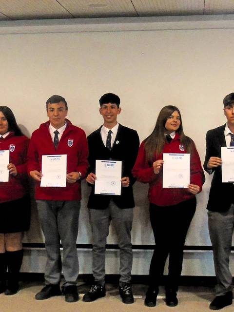 Un grupo de estudiantes posando con certificados en un evento formal.