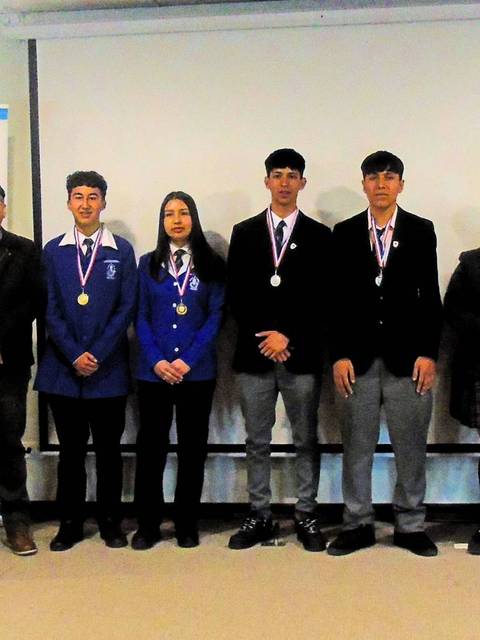 Un grupo de estudiantes con medallas posando en un evento académico.