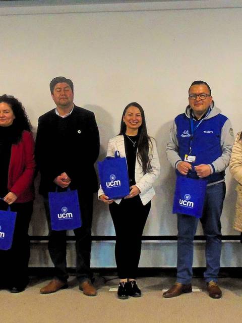 Un grupo de personas posando con bolsas en un evento de la UCM.
