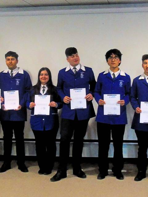 Un grupo de estudiantes en el escenario sosteniendo certificados durante una ceremonia de graduación.