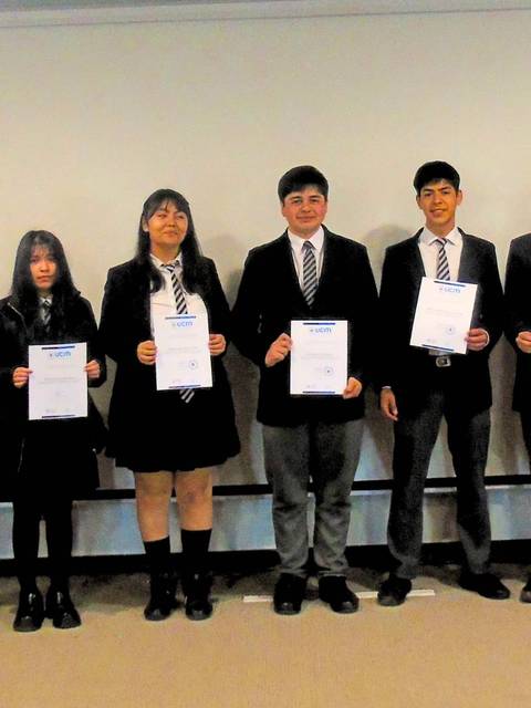 Grupo de estudiantes sosteniendo certificados en un evento escolar.
