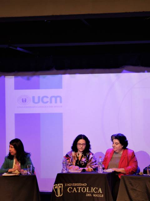 Un grupo de personas en una mesa, discutiendo en un evento académico.