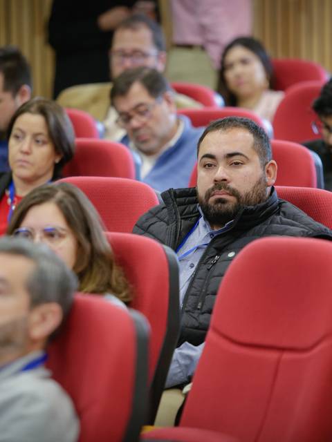 Un grupo de personas en un auditorio escuchando atentamente.
