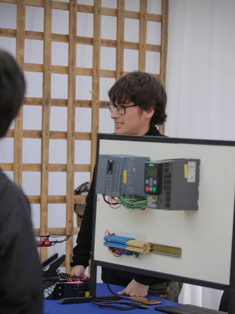 Una persona está mostrando un panel con componentes electrónicos en un evento.