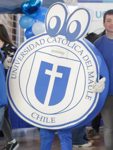Un grupo de tres personas, una de ellas disfrazada de mascota, en un evento de la Universidad Católica del Maule en Chile.