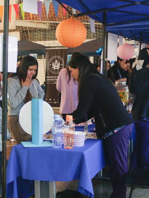 Un grupo de personas interactuando en un evento bajo una carpa azul.