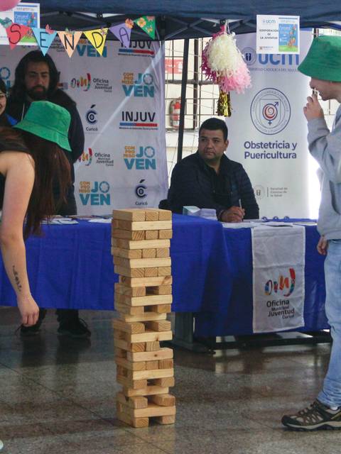 Una actividad recreativa en un evento comunitario donde dos personas juegan con bloques de madera en una atmósfera festiva.