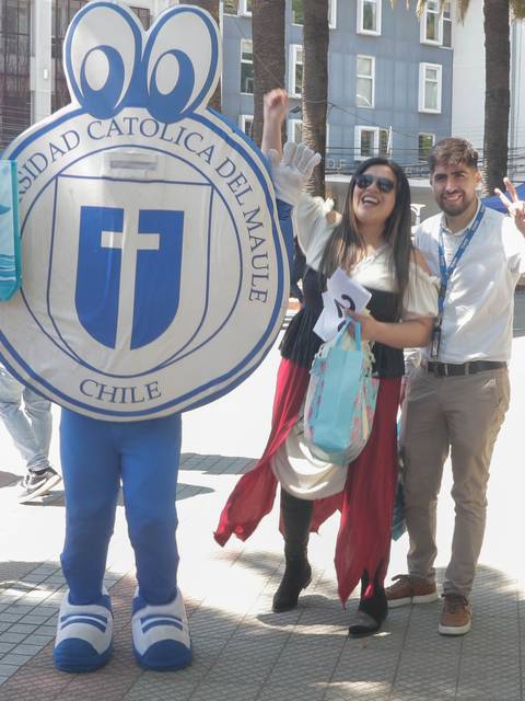 Un grupo de jóvenes celebra en un evento al aire libre con un personaje disfrazado que representa a una universidad.
