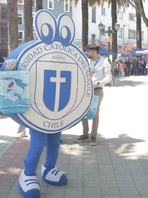 Un grupo de personas disfrazadas en un evento al aire libre con un dinosaurio y una mascota.